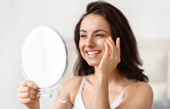 Analytical millennial woman focused on skincare, closely examining her eyes in a bathroom, anti-ageing skin care